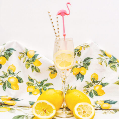 spiked lemonade mimosas on counter with lemonade towel and pink flamingo straw